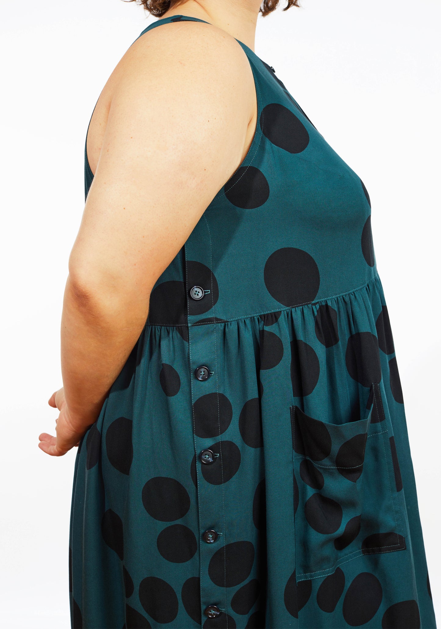 Side view of Austin Dress in teal dot print showing gathered skirt, pocket, and side button band.