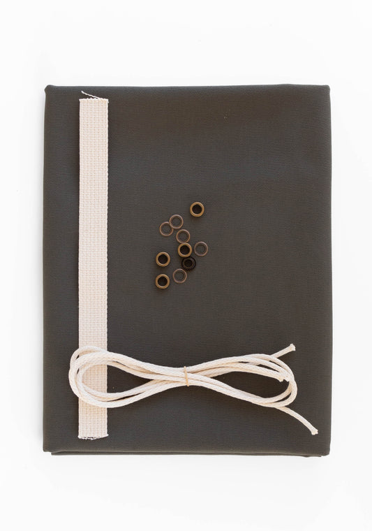 Flatlay of Field Bag kit in pewter green canvas with cotton web strap, cotton cord, and antique brass grommets.