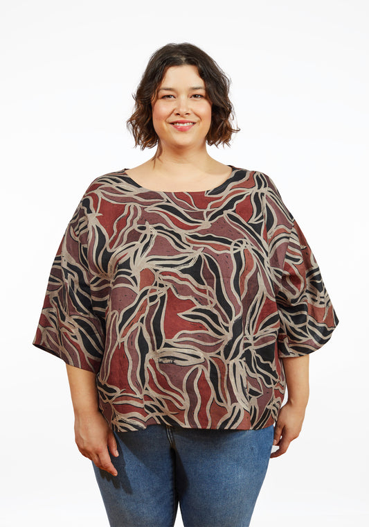 Front view of Corin Top in batik print with curved neckline and elbow-length drop shoulder sleeves, worn by smiling model.