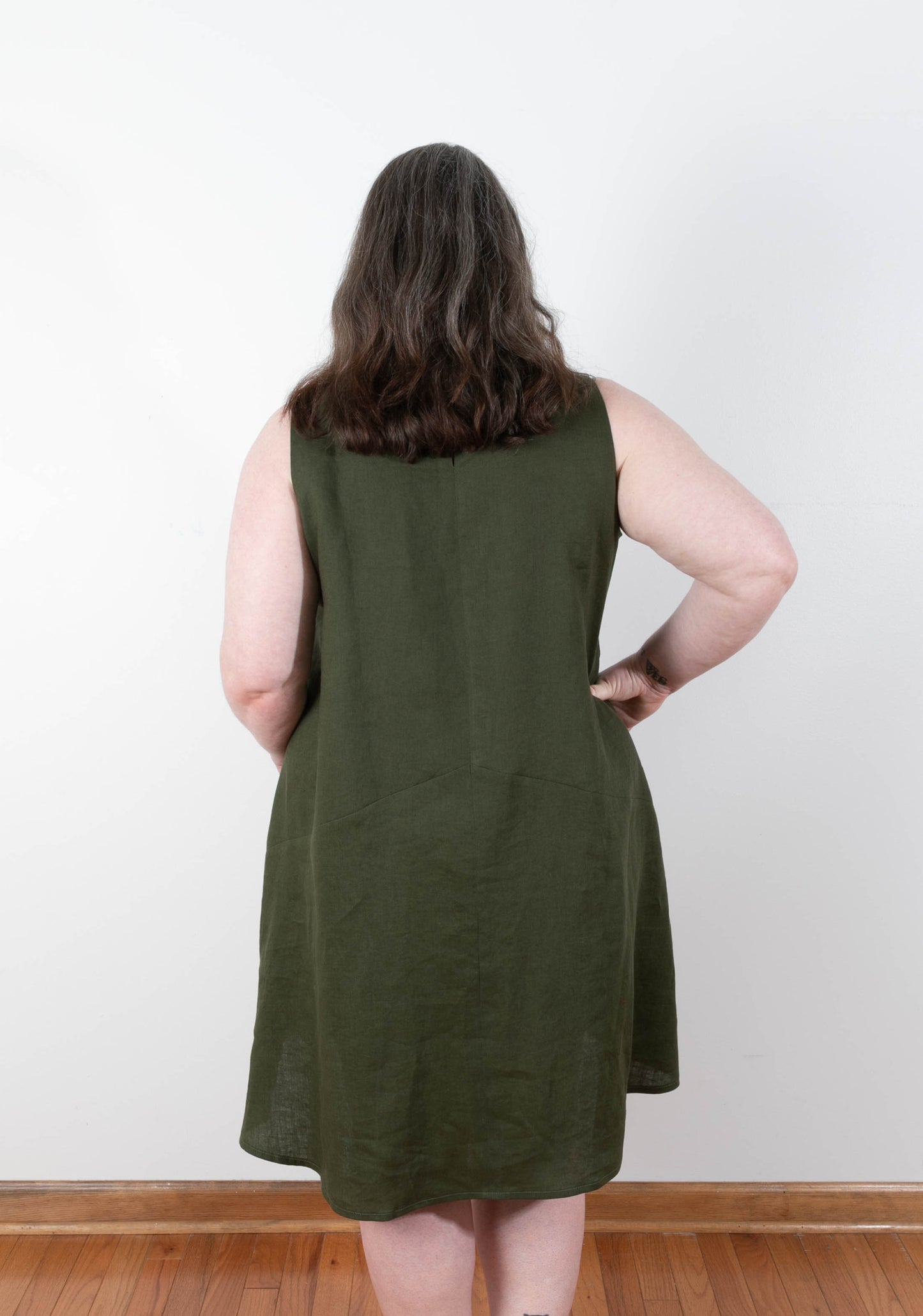 Back view of sleeveless Farrow Dress in solid olive linen showing center back seam and flared hem.