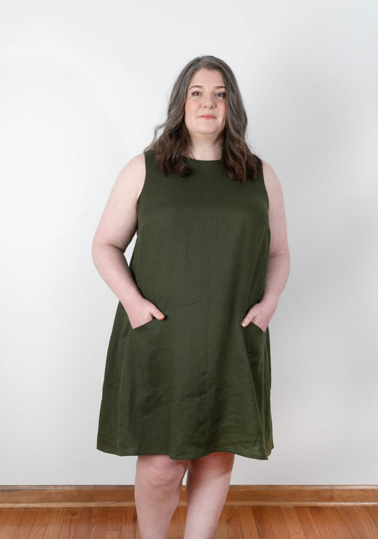 Front view of Farrow Dress in size 14-32, sleeveless version in solid olive linen with angled seam and pockets.