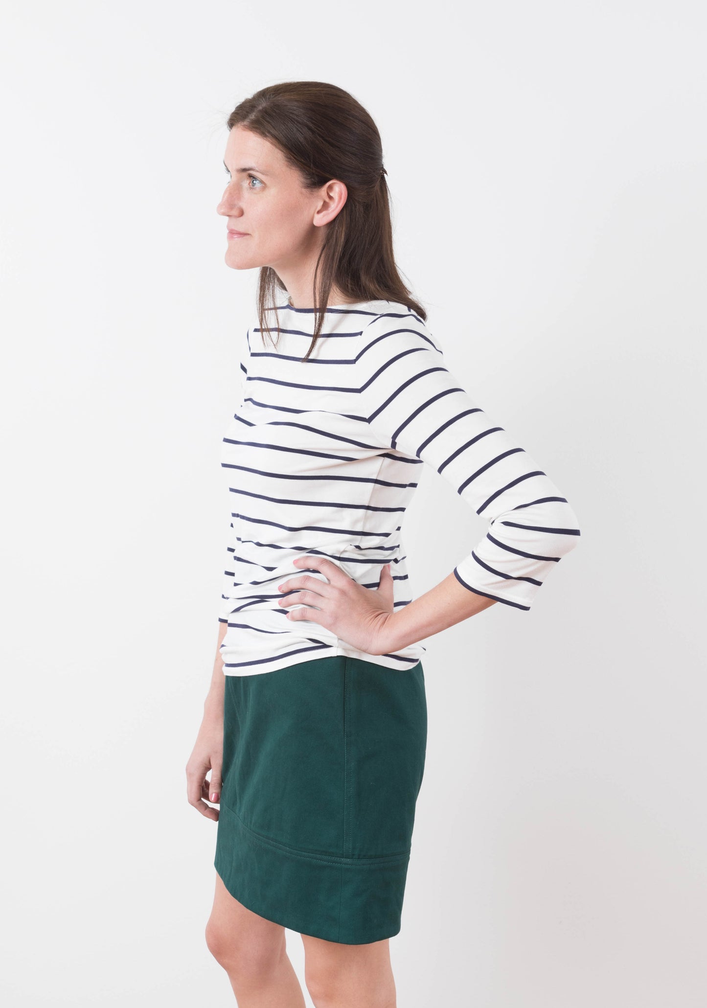 Side view of Moss Skirt in dark green twill styled with white and navy striped knit top.