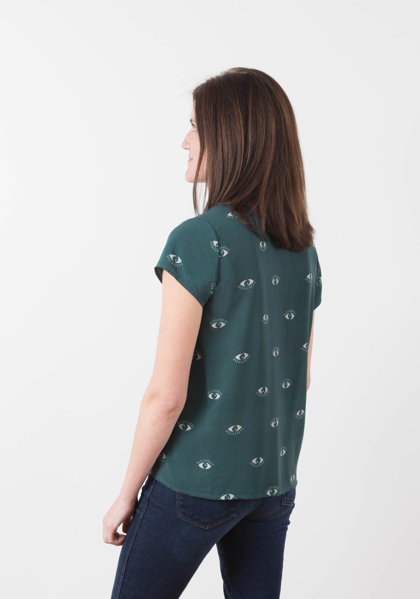 Model wearing green Scout Tee with eye print from back view, turned slightly.