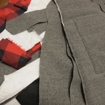In-progress gray wool coat with red buffalo plaid flannel lining, cut pattern pieces spread on a table