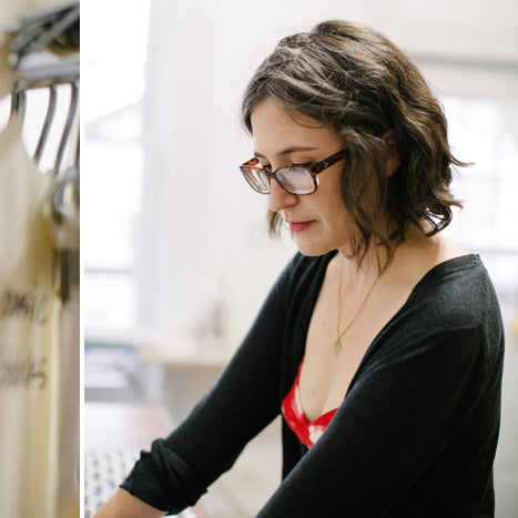 Vintage dress form with pattern pieces in a sewing studio, alongside a woman in glasses reviewing pattern drafting materials