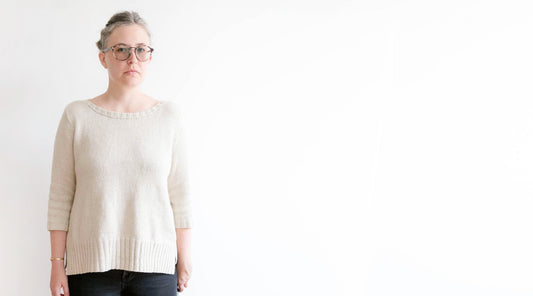 Cream ribbed knit bateau-neck sweater with three-quarter sleeves and fitted ribbed hem, worn with dark jeans