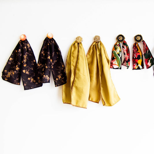 DIY earring tutorial: three pairs of fabric scrap earrings with vintage buttons, in black floral, gold, and colorful floral