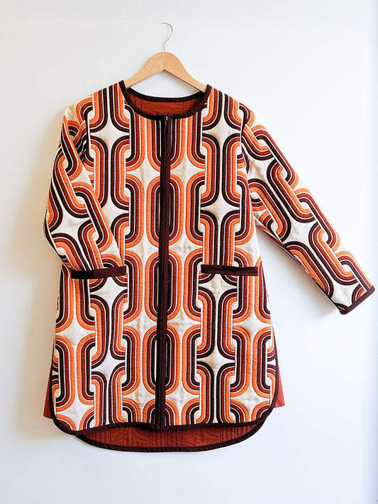 Lengthened Tamarack Jacket hack in orange and brown geometric print with zipper front, patch pockets, wooden hanger