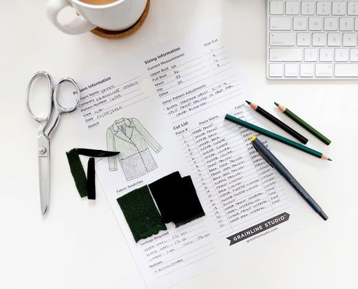 Image of a pattern card on a white desk with colored pencils, scissors, and fabric scraps