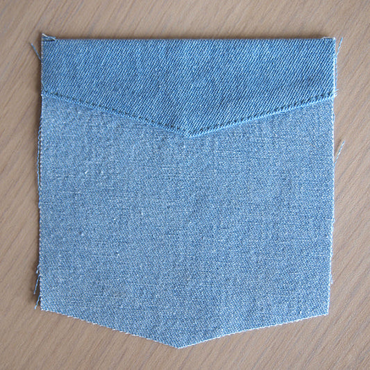 Alder Shirtdress light-wash denim patch pocket with pointed bottom and topstitched header, showing raw edges before attachment