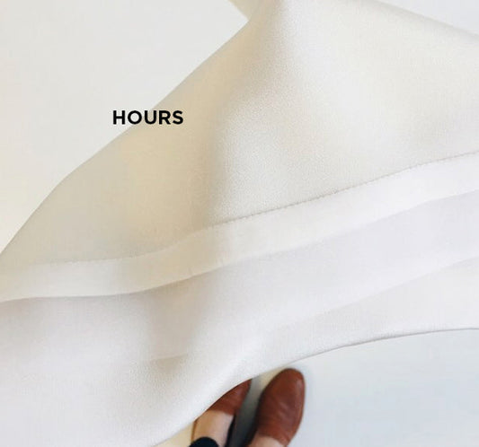 lose-up of cream fluid fabric being held and folded to show drape and texture, with the word HOURS overlaid as a text graphic