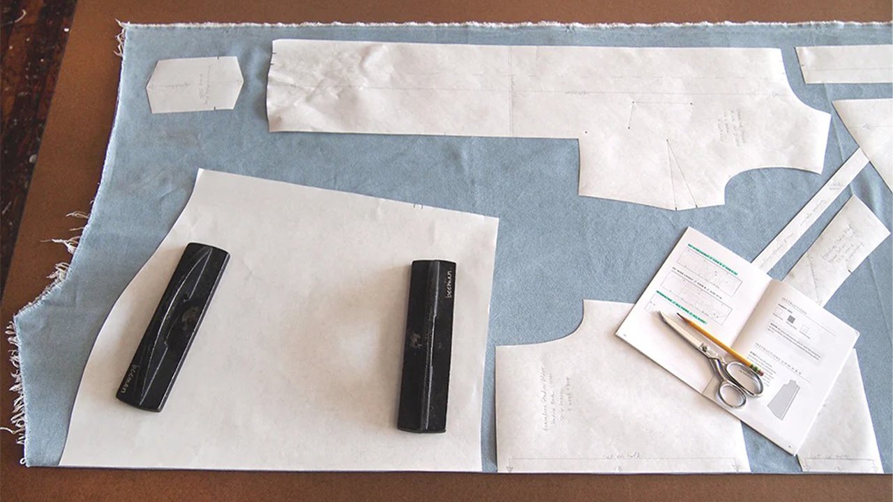 Alder pattern pieces laid out on light blue denim with pattern weights, scissors, and instruction booklet on cutting table