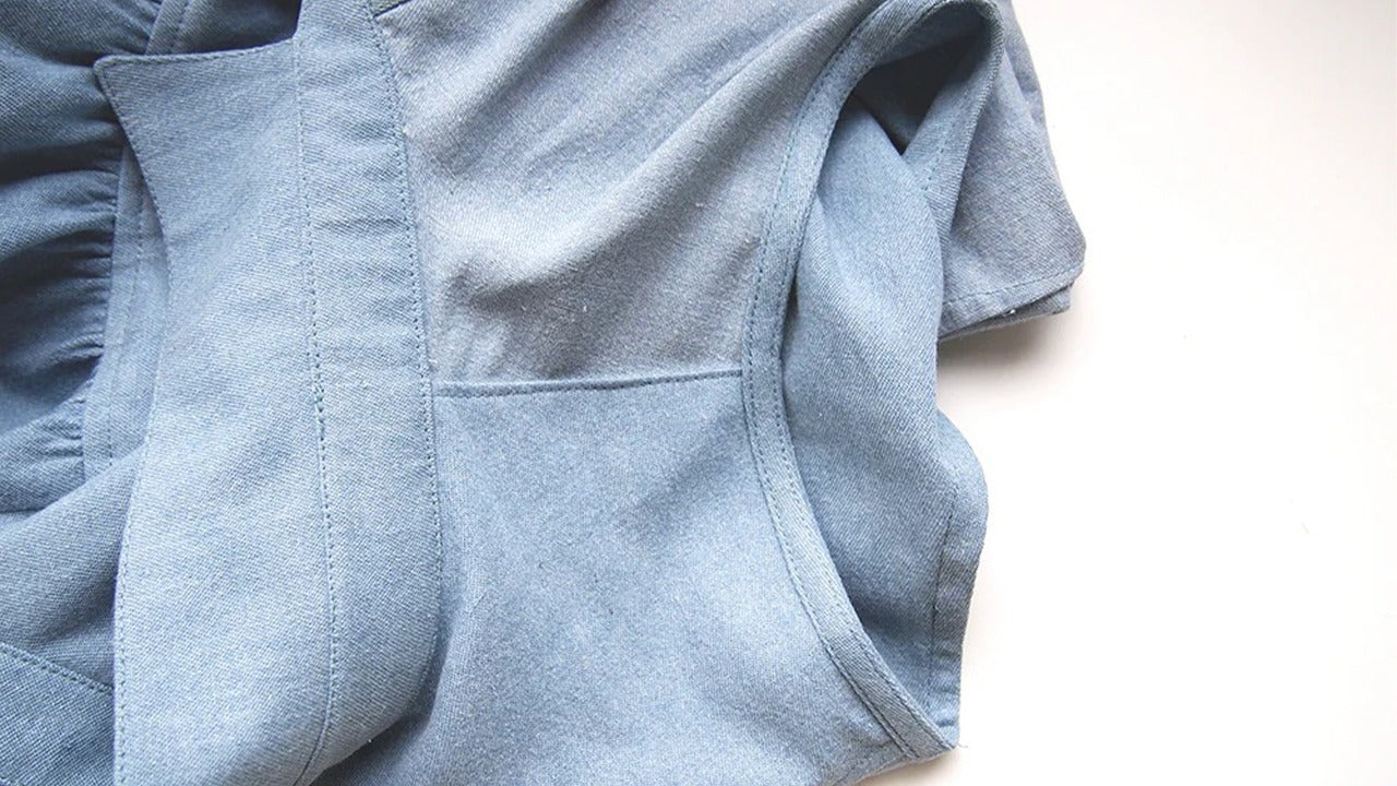 Alder shirtdress in light blue denim showing finished bias-faced armhole with clean edgestitching and underside binding visible