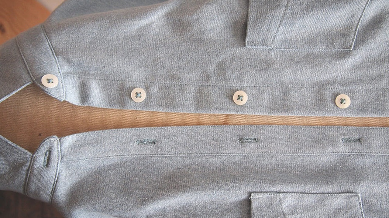 Completed Alder shirtdress in gray denim showing aligned button bands with cream buttons and corresponding buttonholes