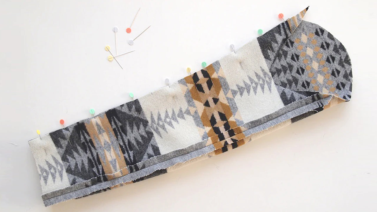 Two-piece sleeve construction showing geometric print wool upper and lower sleeve pieces pinned together with colorful pins