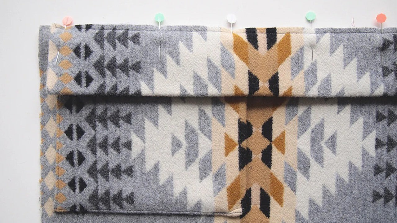 Front band pinned to geometric print wool coat with colorful pins marking placement along folded edge