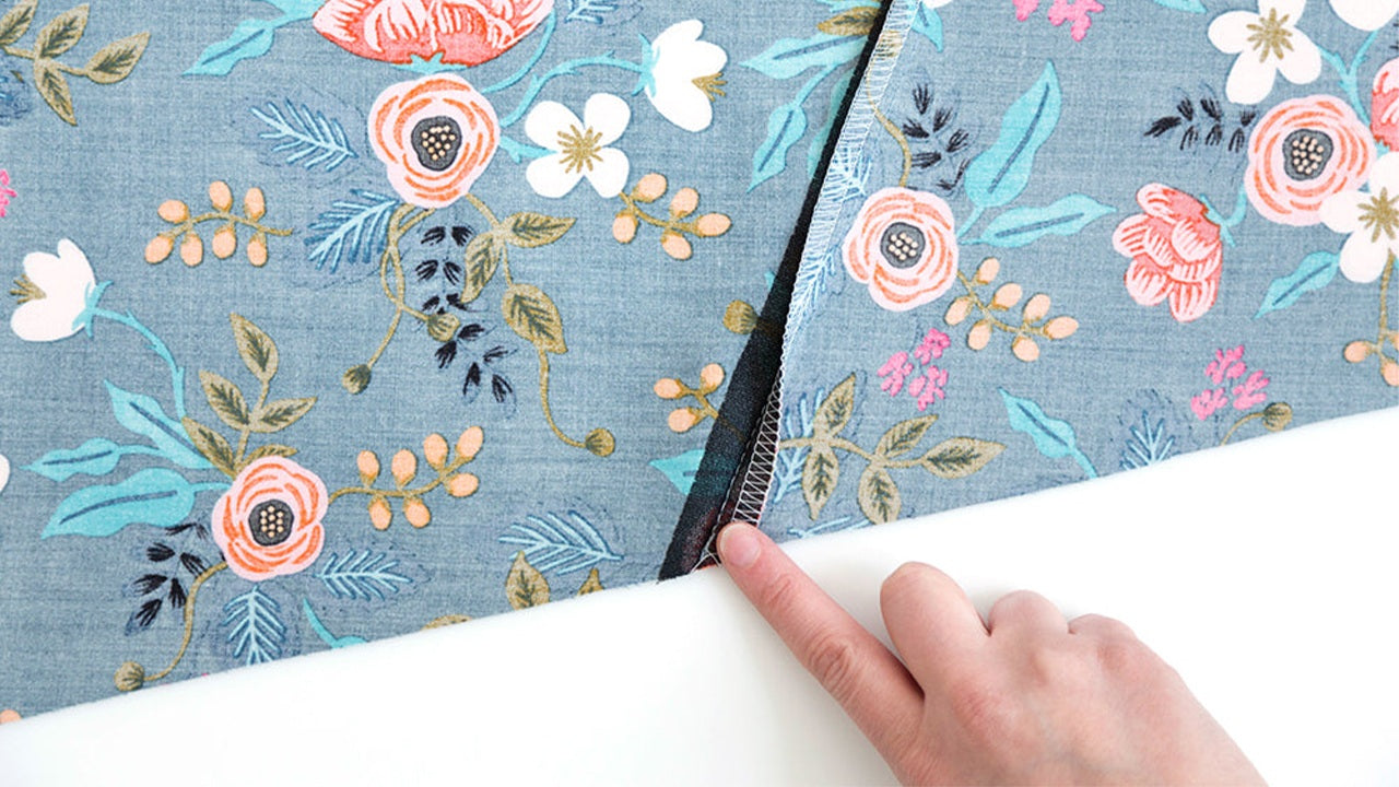 Serged edge of center back seam on blue floral rayon Farrow Dress fabric showing seam finishing technique on angled diagonal seam.