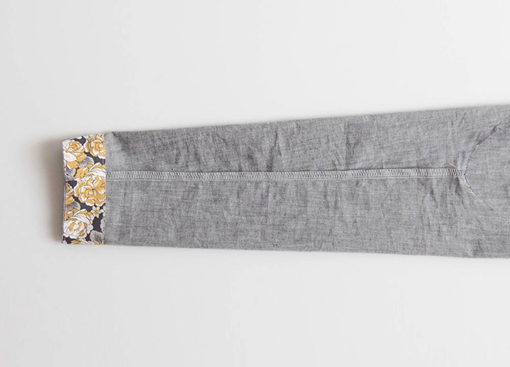 Gray linen Farrow Dress sleeve turned inside out showing positioning technique for sewing narrow bracelet-length sleeve facing or hem at machine.