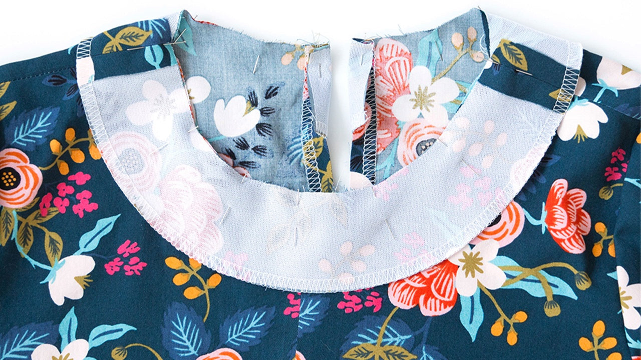 Neckline facing pinned to Farrow Dress neckline showing proper alignment at center back opening on navy and light blue floral fabrics.