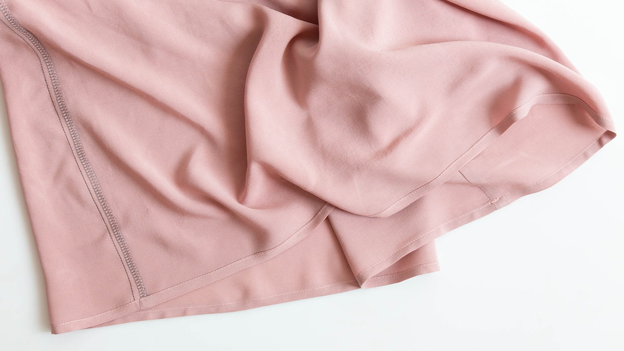 Felix Dress hem detail in pink fabric showing double-fold hem with serged seam allowance and stitching