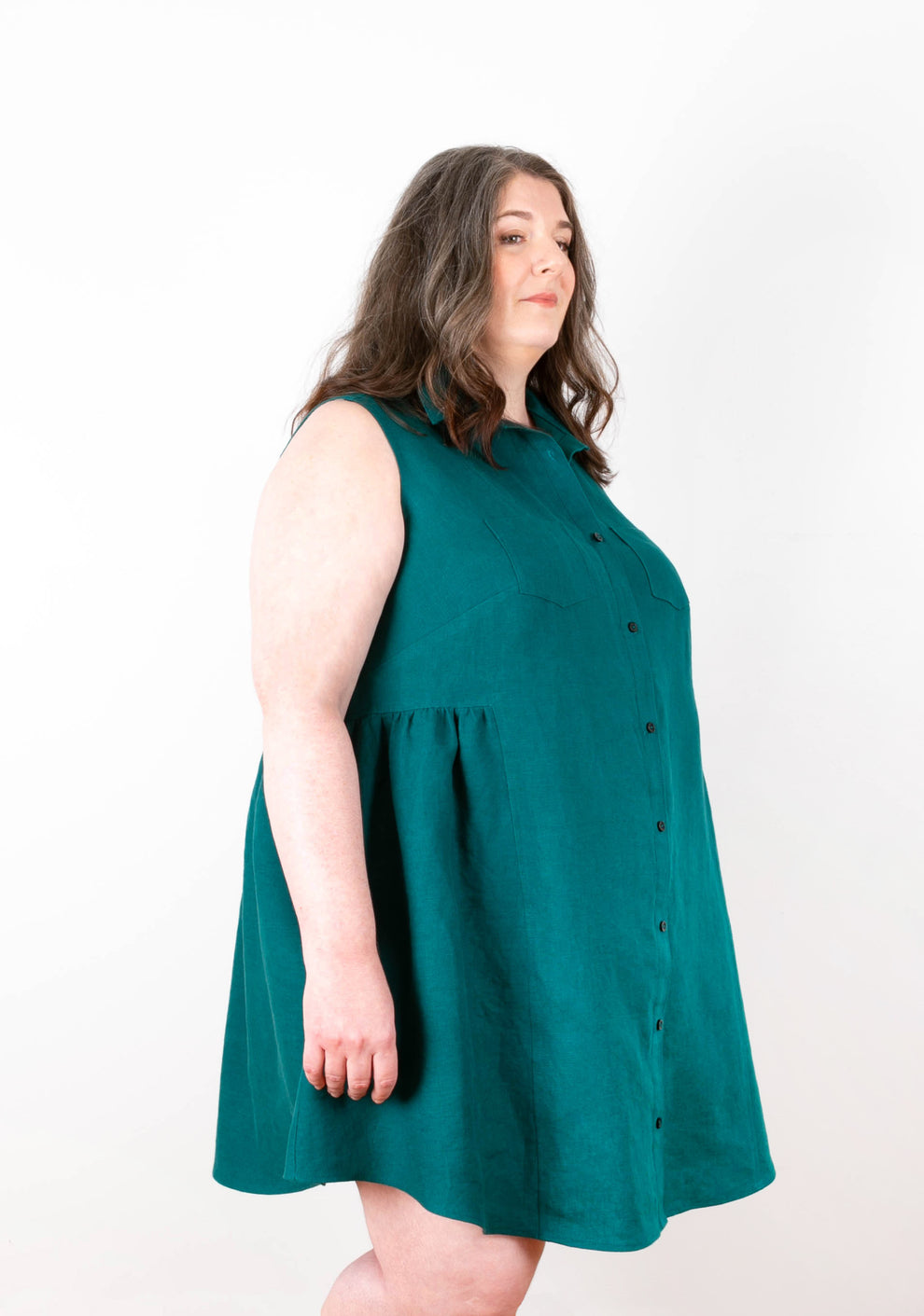 Side angle of Alder Shirtdress View B in teal linen showing armhole, yoke shaping, and flared skirt.