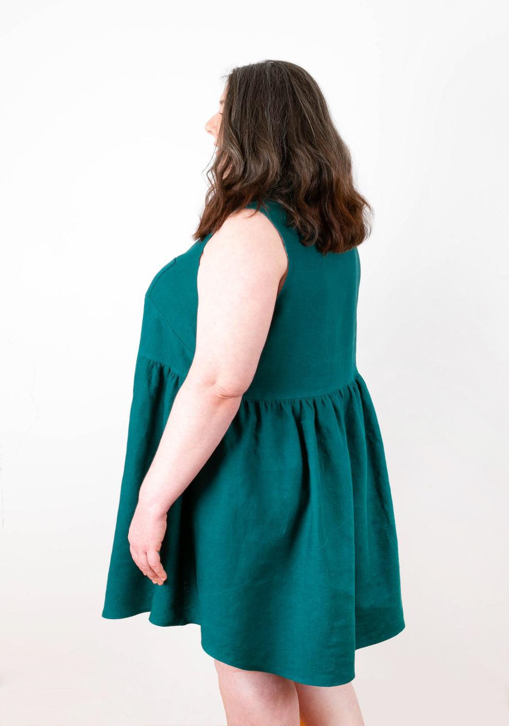 Side view of Alder Shirtdress View B in teal linen highlighting gathered waist and back shaping.
