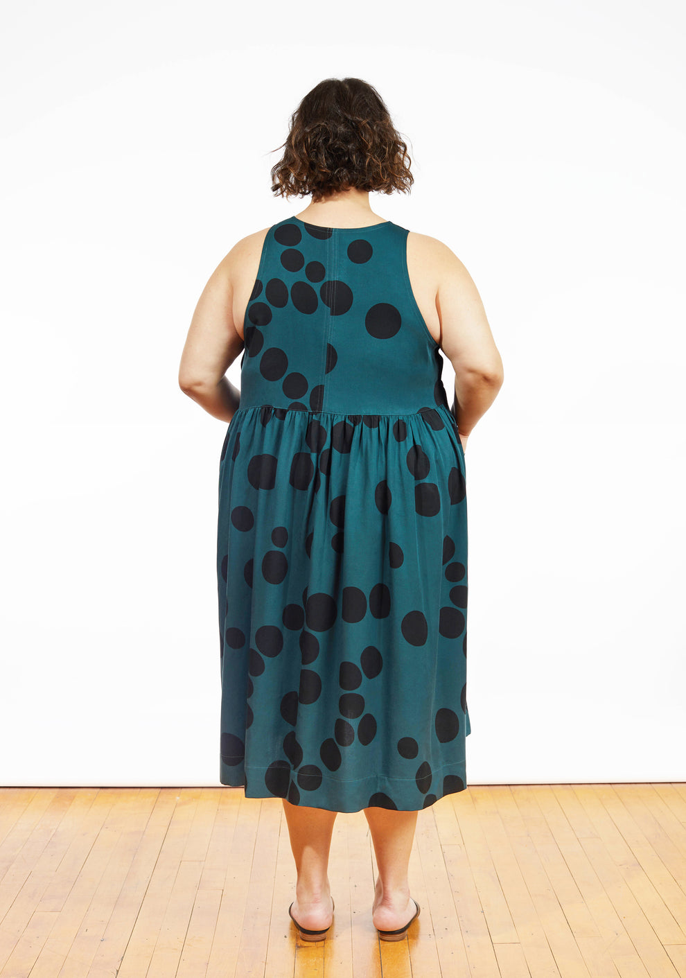 Back view of Austin Dress in teal dot print showing sleeveless bodice and gathered skirt.