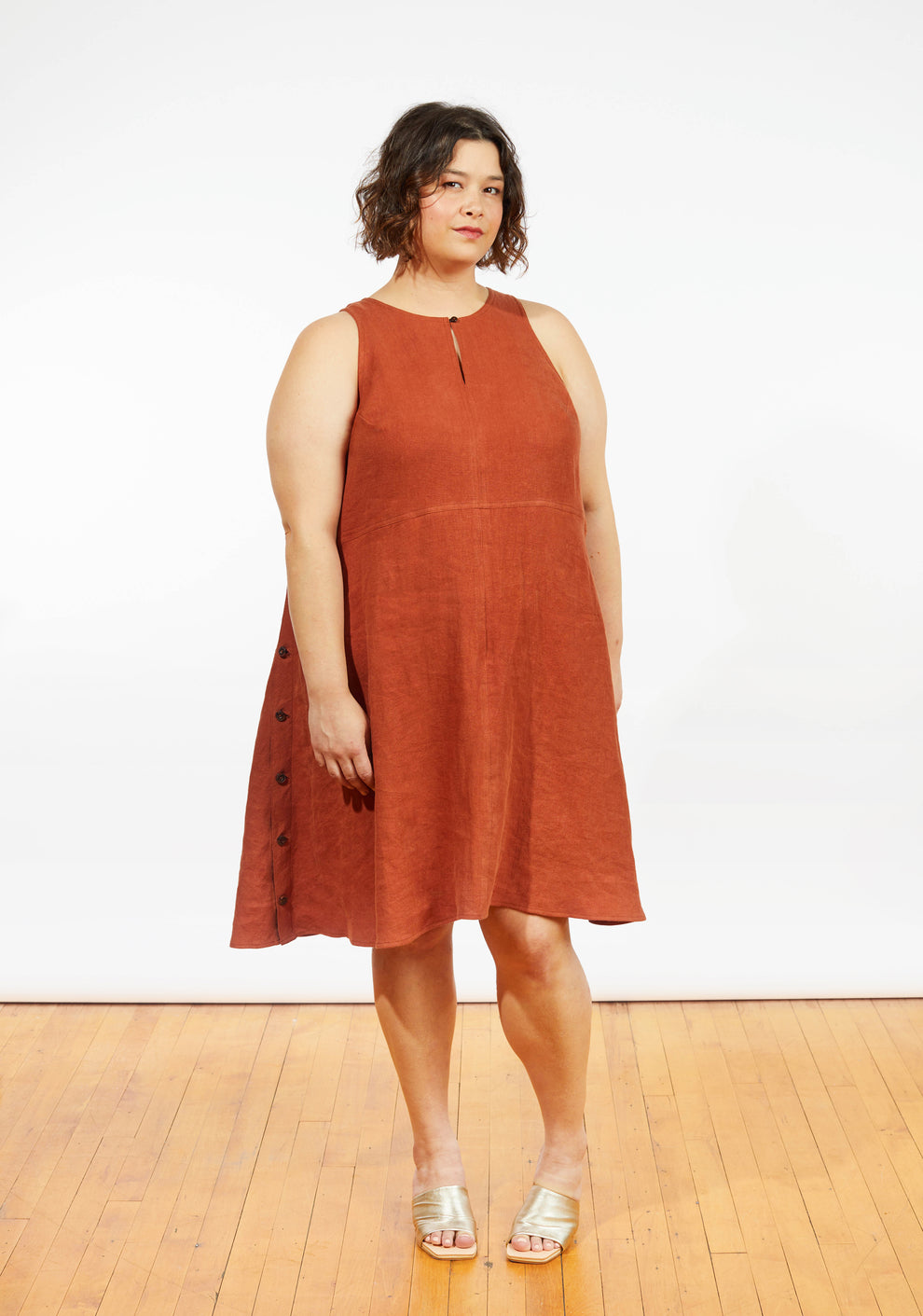 Front view of Austin Dress in rust linen, sleeveless A-line style with side buttons and keyhole neckline, worn by model.
