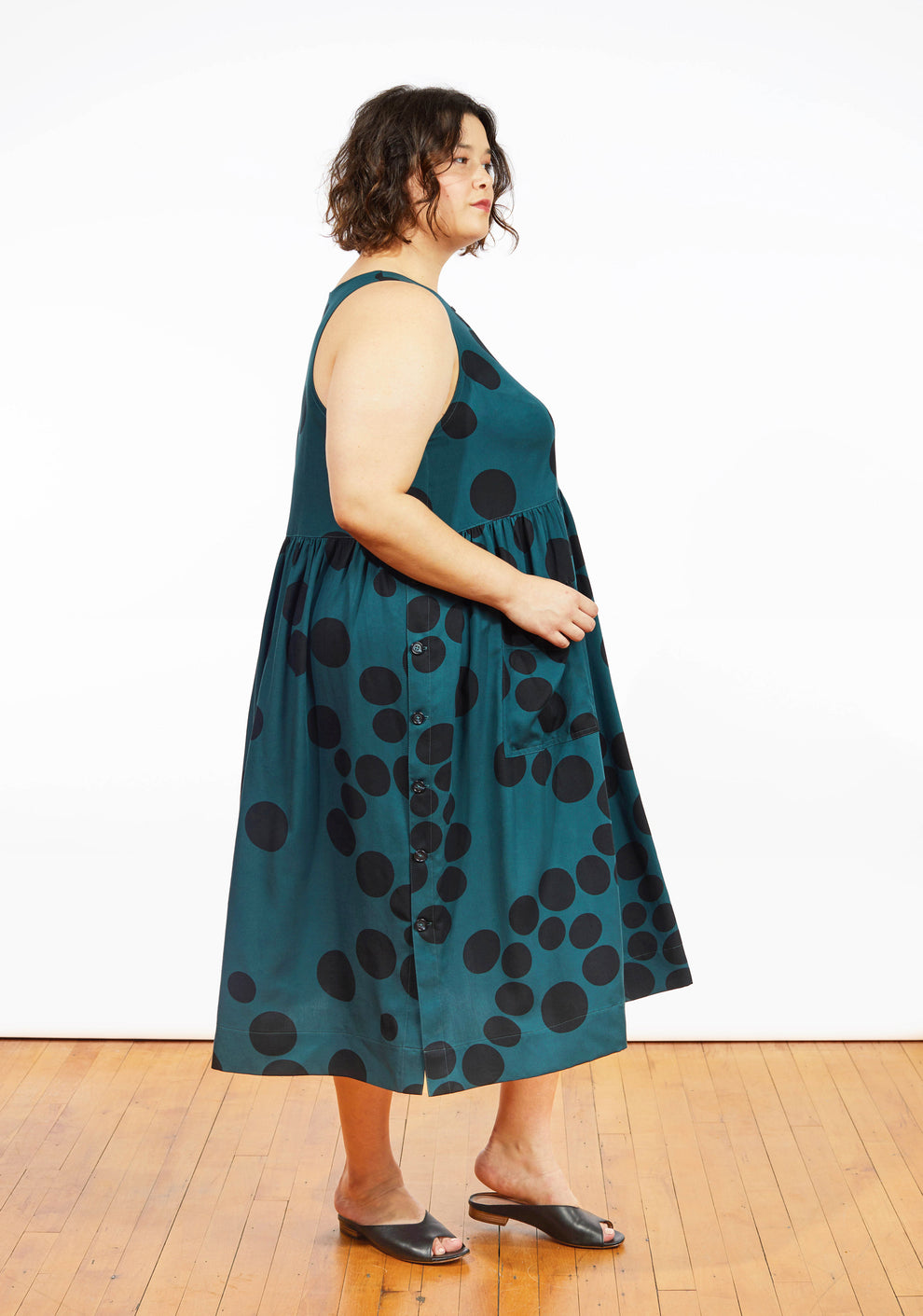 Angled side view of Austin Dress in teal dot print showing sleeveless bodice and patch pocket.