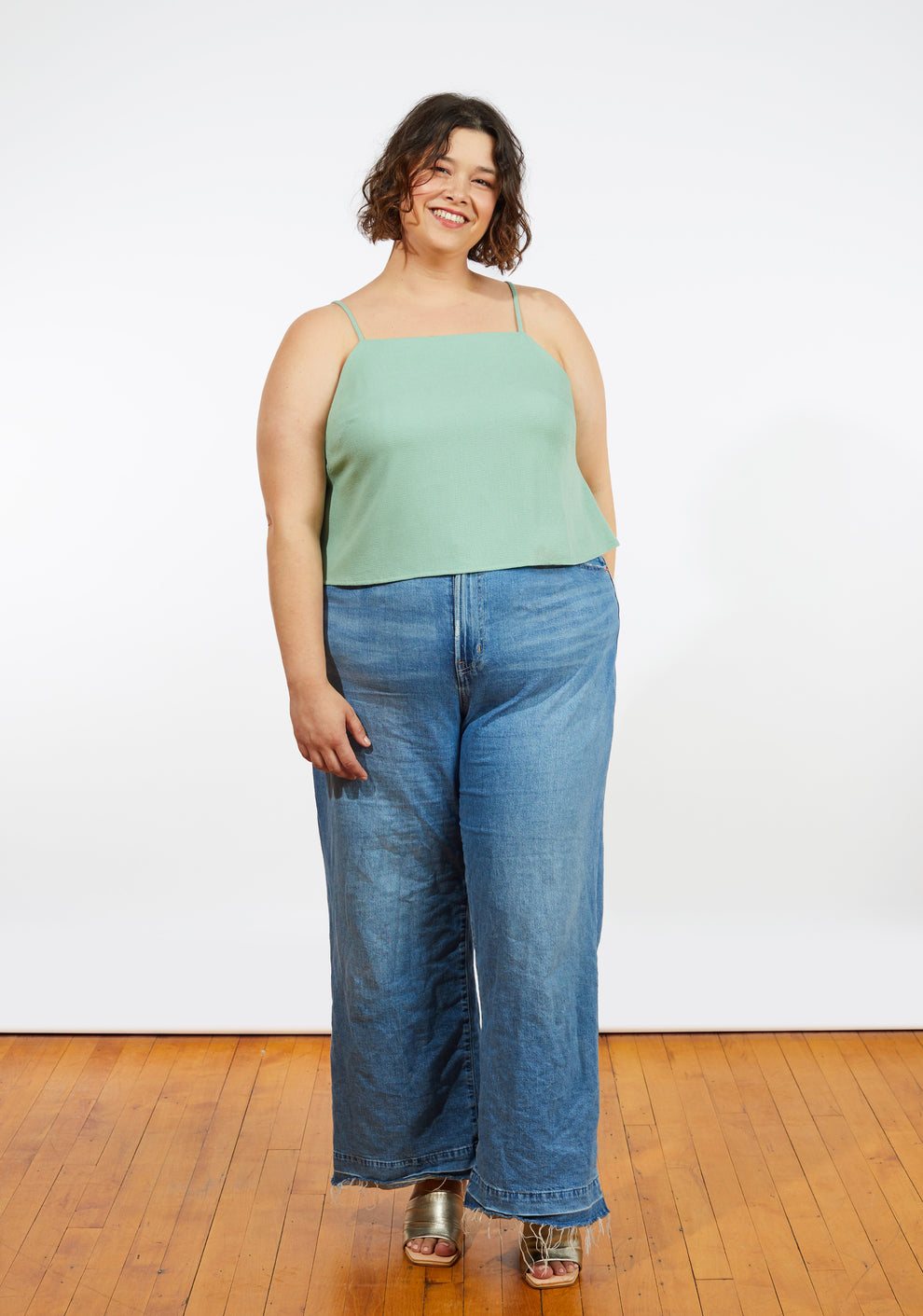 Full body front view of model in green Myra Top paired with jeans, featuring square neckline and spaghetti straps.