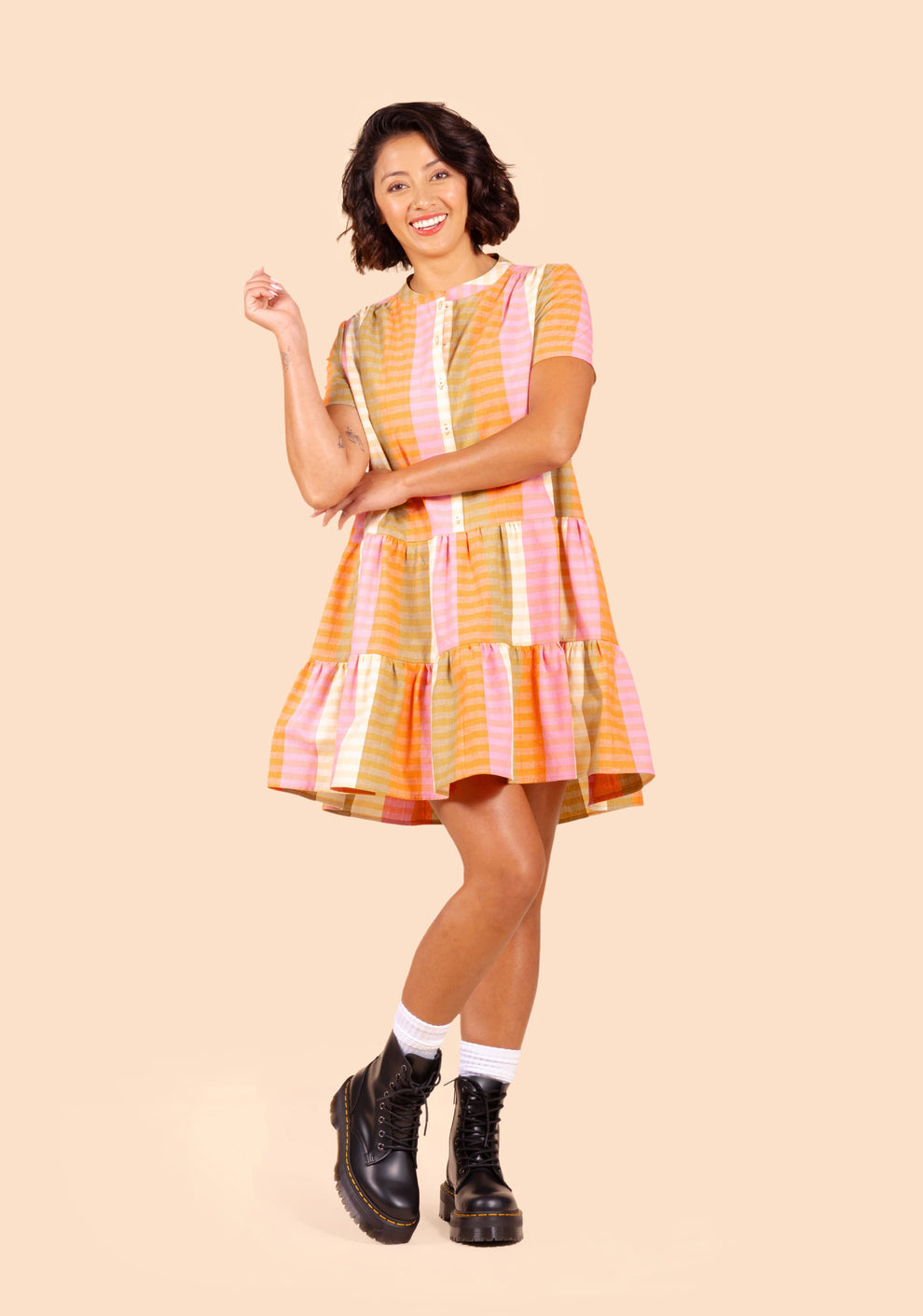 Model posing in front view of the Poppy Dress with button front and vibrant striped design.
