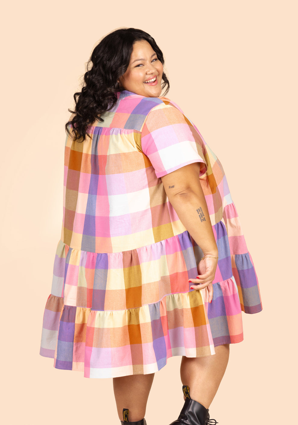 Back angle view of model wearing short Poppy Dress View A in colorful plaid cotton.