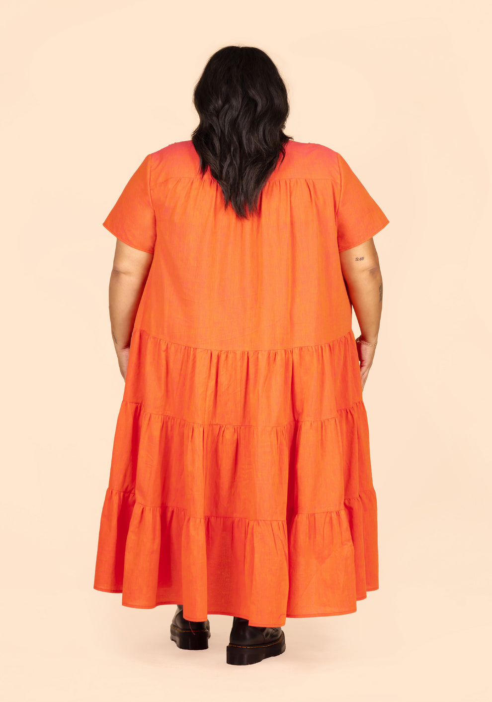 Back view of long Poppy Dress View B in orange linen, featuring short sleeves and gathered tiers.