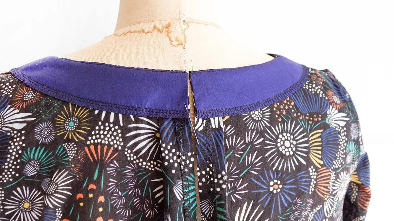 Close-up of Hadley View A jewel neckline on dress form showing attached purple facing with keyhole opening at center back