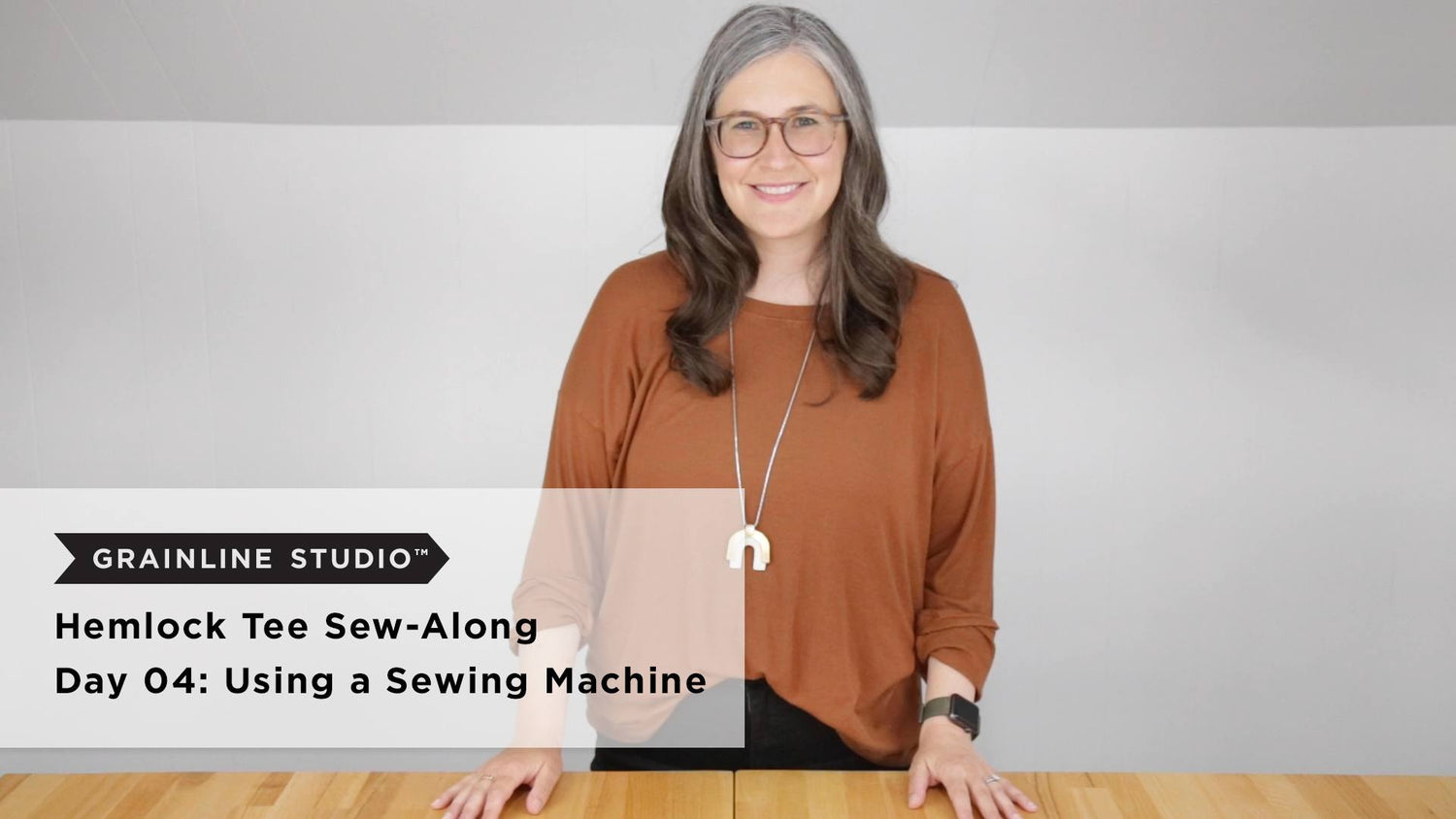 Hemlock Tee Sew-Along Day 04 thumbnail, woman standing at wood table for sewing machine lesson