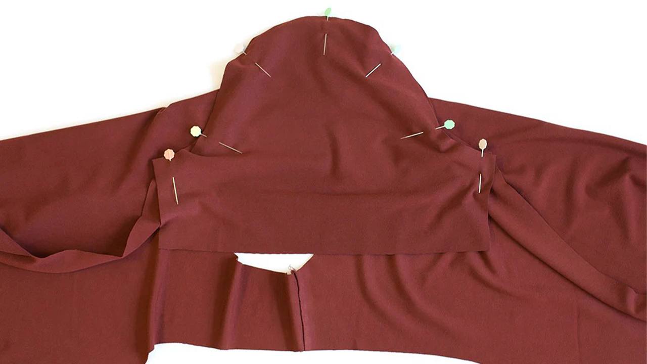 Brick red Lark Tee body with sleeves pinned into armholes showing shoulder seams and underarm construction ready to sew