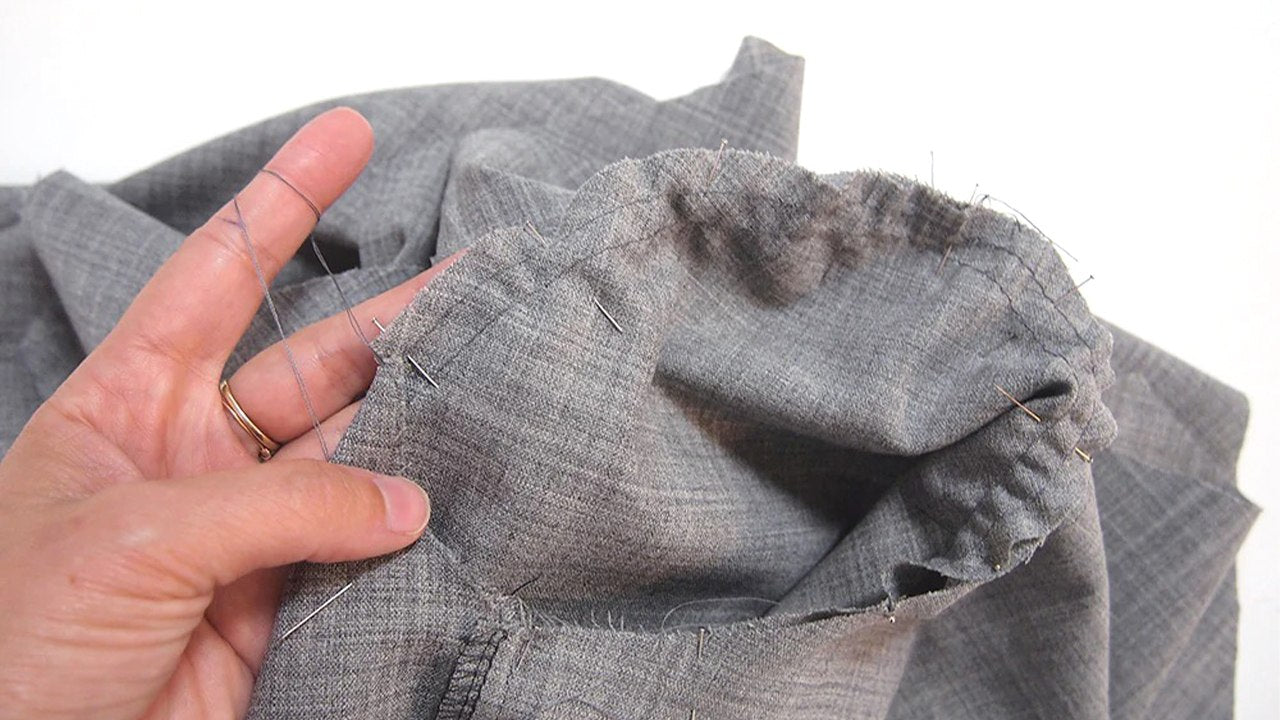 Hand holding Morris Blazer sleeve showing pinned sleeve cap with gathering eased into armhole in gray fabric