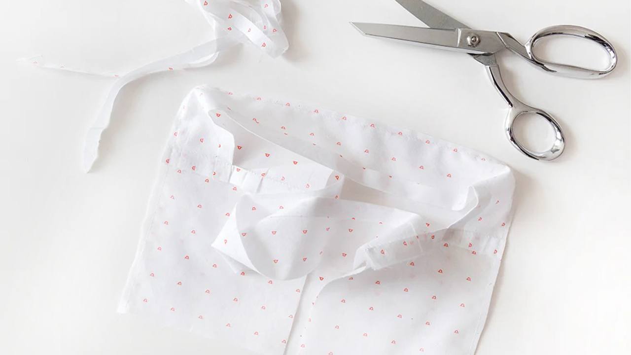 Completed dopp kit lining in white fabric with pink hearts print laid flat with embroidery scissors beside it