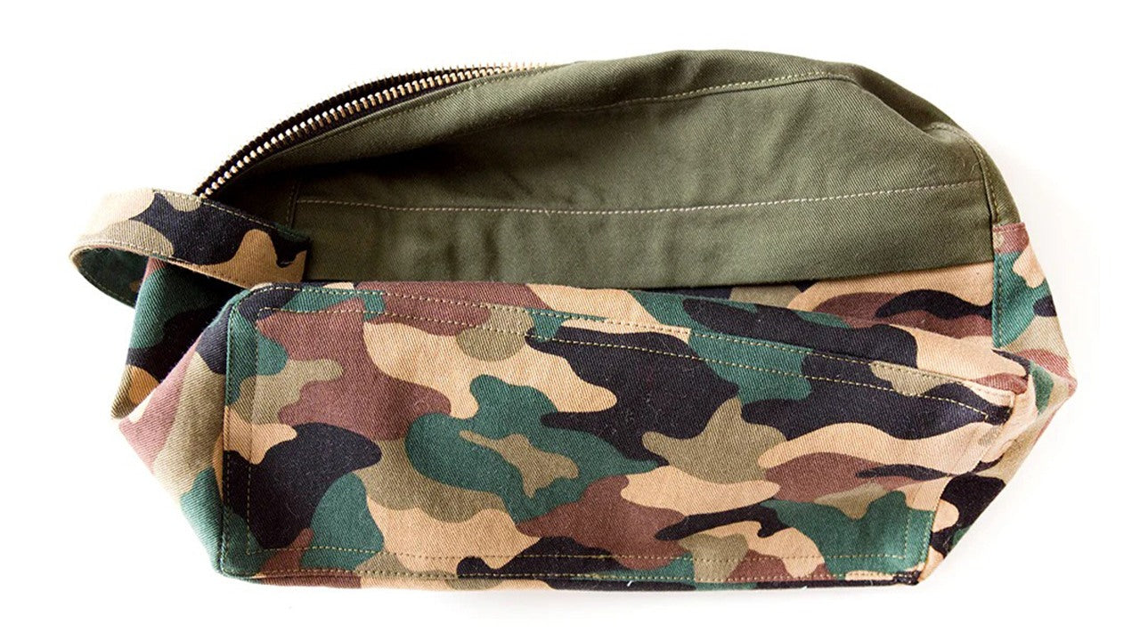 Three-dimensional dopp kit body in camo and olive green showing main zipper, front pocket zipper, and topstitched seams