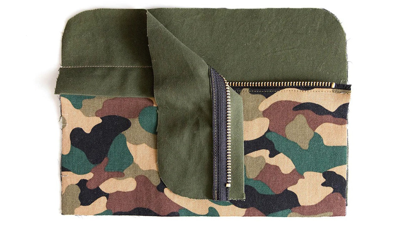 Assembled Dopp Kit front panel in camo and olive green showing zippered top panel, front pocket with zipper laid flat