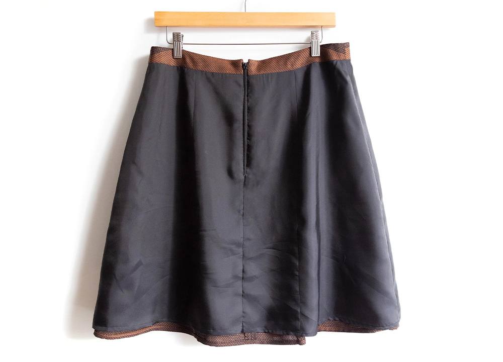 Lined Reed Skirt on hanger showing black outer fabric with brown twill lining visible at waistband and hem edges