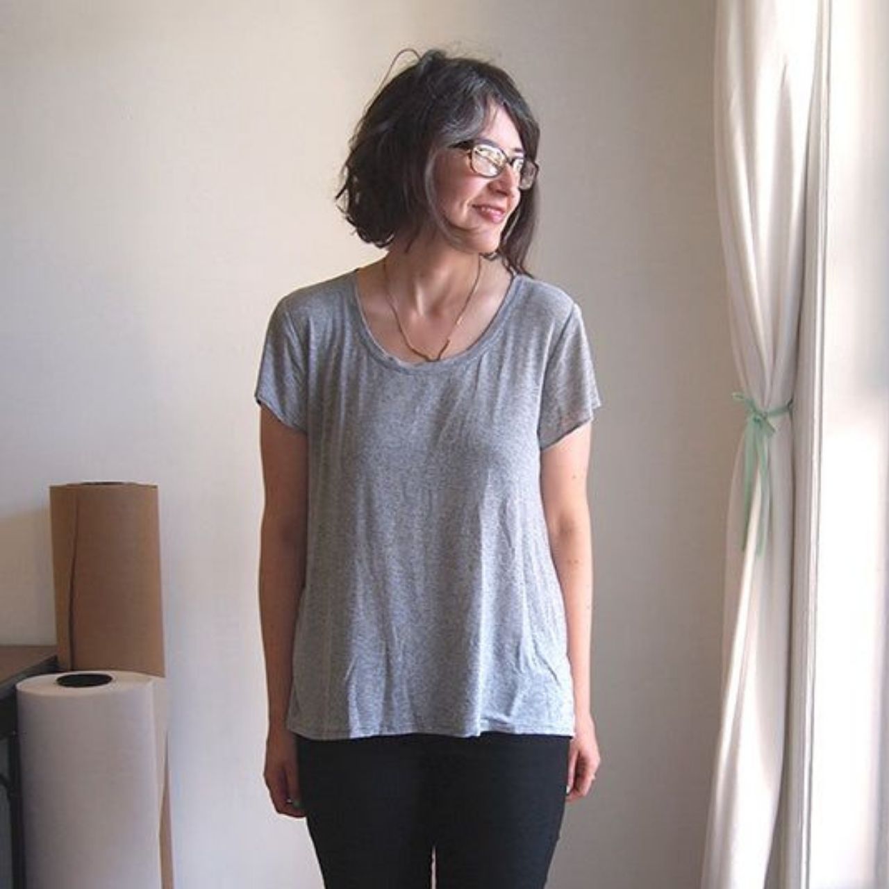 Woman wearing a Scout Tee sewn in heathered gray knit fabric with a scoop neckline and cap sleeves, styled with black pants.