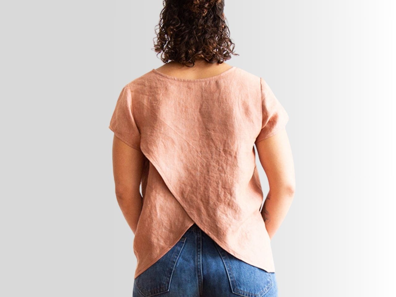 Back view of a Scout Tee with tulip split back modification in dusty rose linen, styled with jeans.