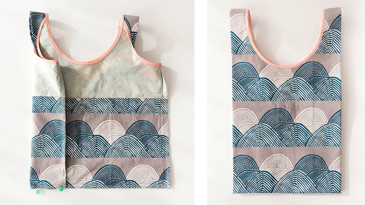 Completed Stowe Bag in teal wave print with pink binding showing front with side gussets and organized pockets