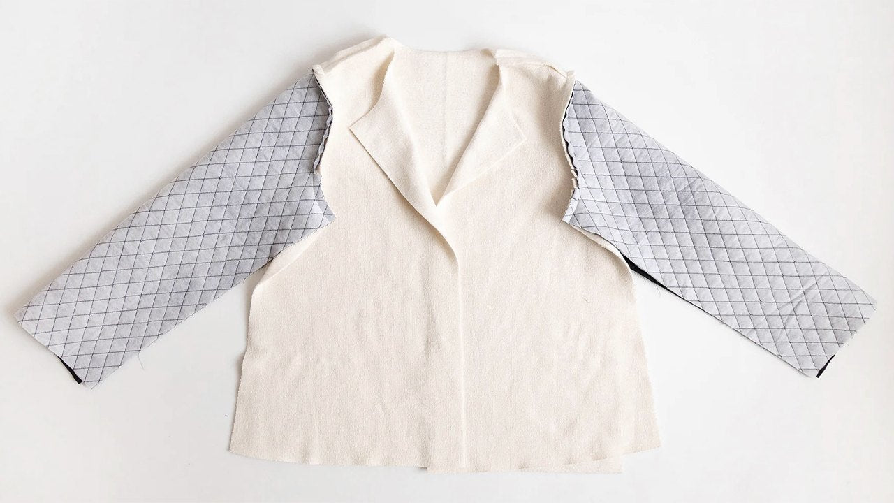 Thayer Jacket lining laid flat showing cream wool body with quilted gray sleeve lining and collar construction in progress