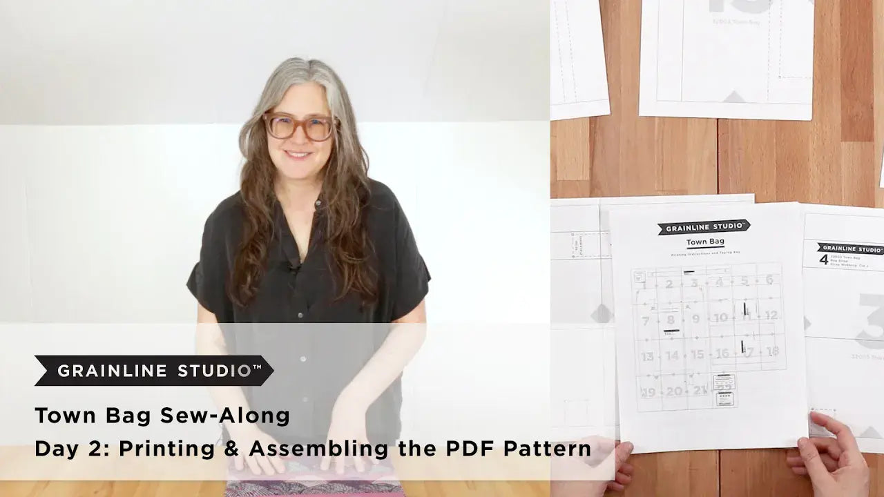 Woman beside an assembled Town Bag PDF pattern and printing instructions spread out on a wood surface.