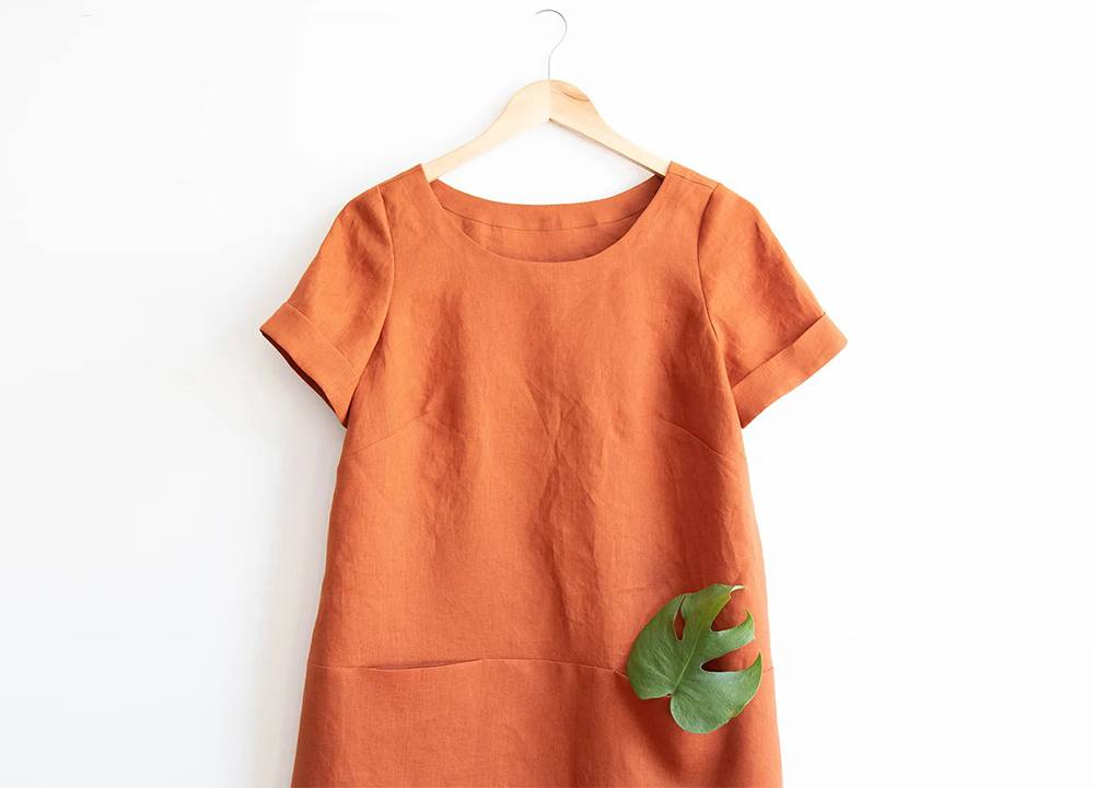 Uniform tunic in rust linen on hanger showing short cuffed sleeves with 1½ inch fold-up cuff detail