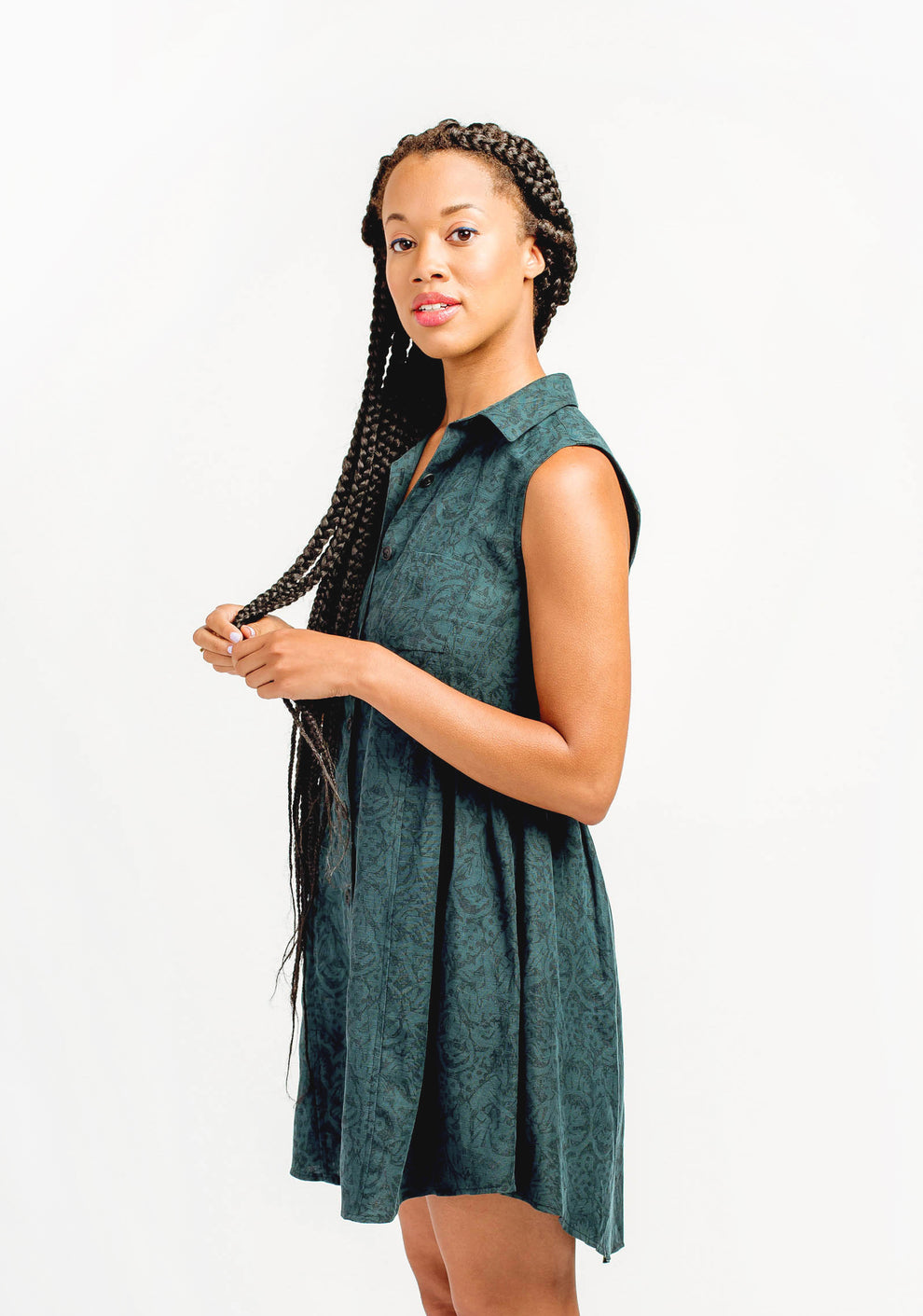 Side view of sleeveless green Alder Shirtdress with fitted bodice and gathered skirt.