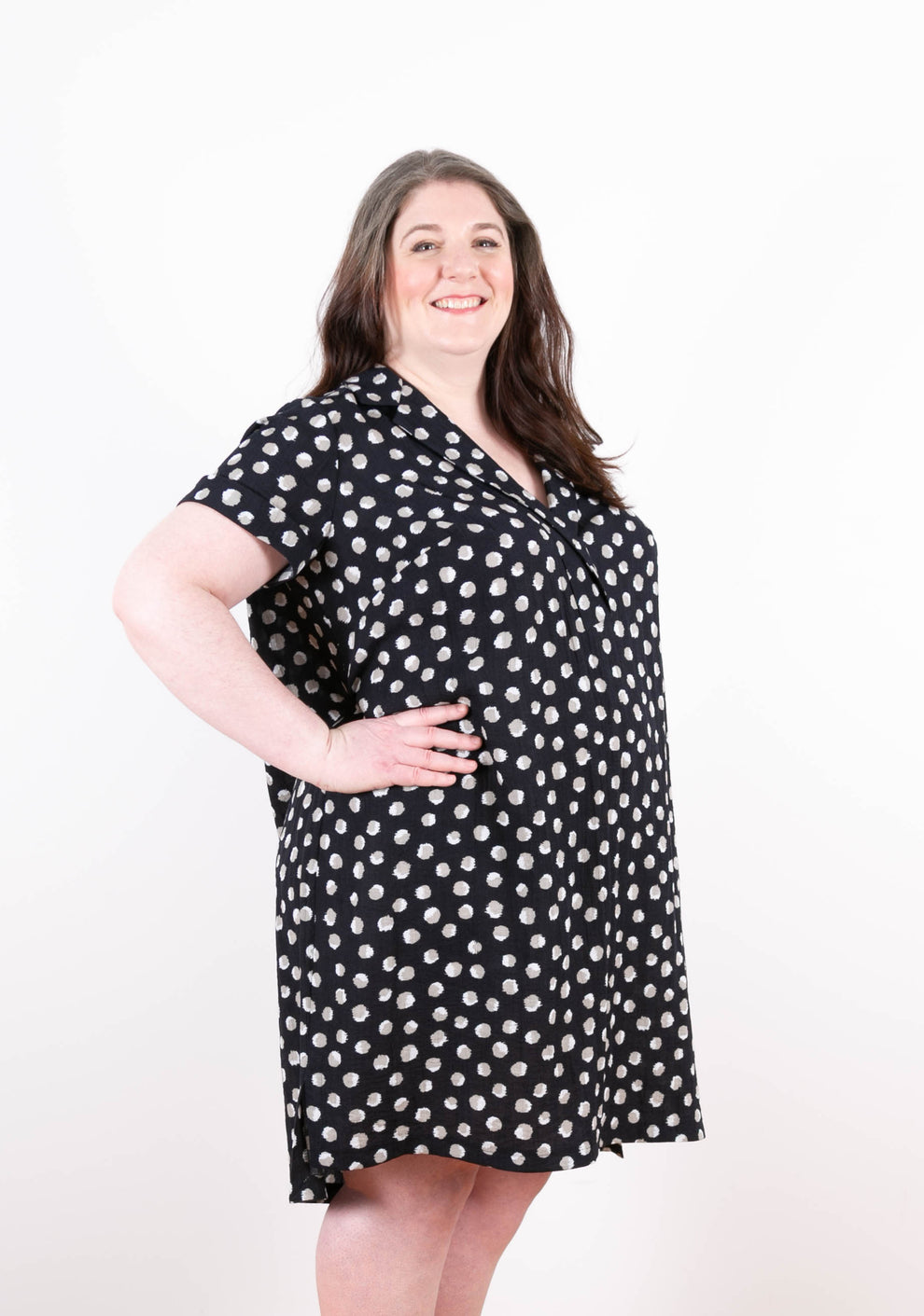 Three-quarter front view of polka dot Augusta Dress with notched collar and side slit.