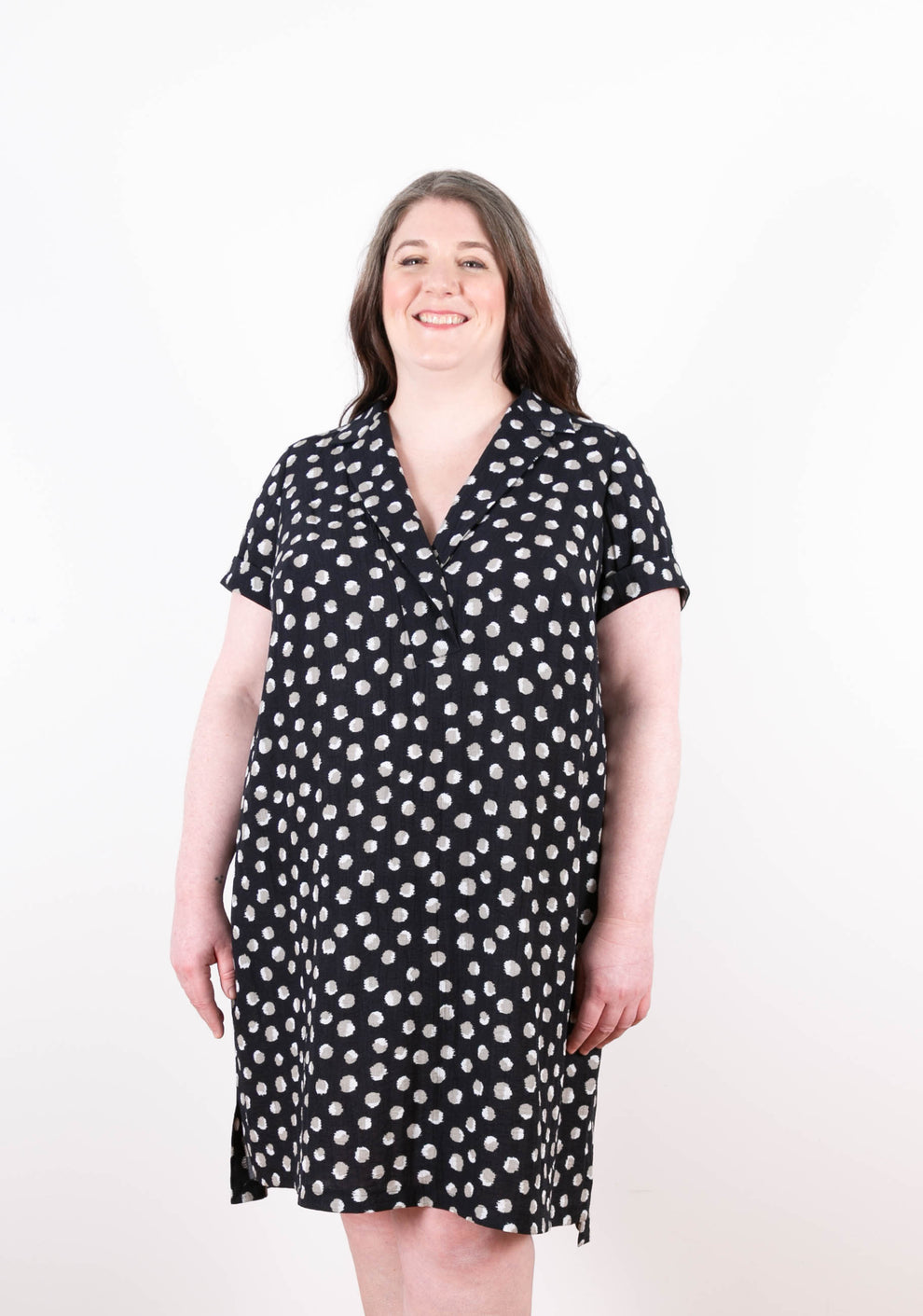 Model: Size 20, 5'5" | Front view of Augusta Dress in black with white dot print, short sleeves, and split neckline.